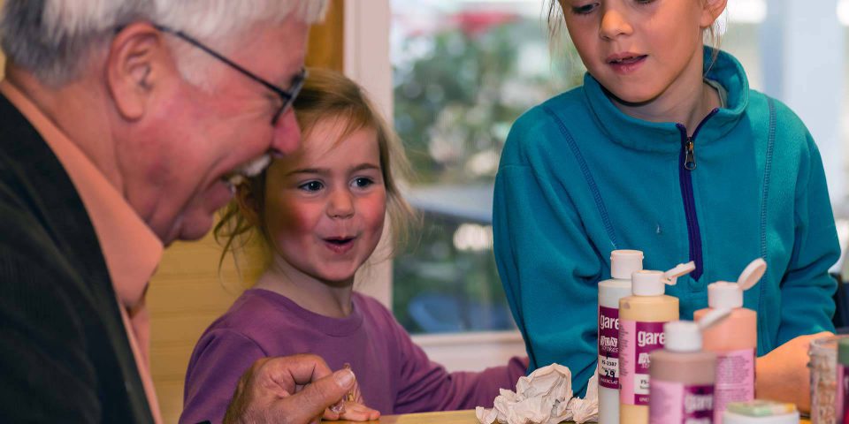 Older man helping two girls paint pottery at Pottery Bayou in Winona Lake, IN