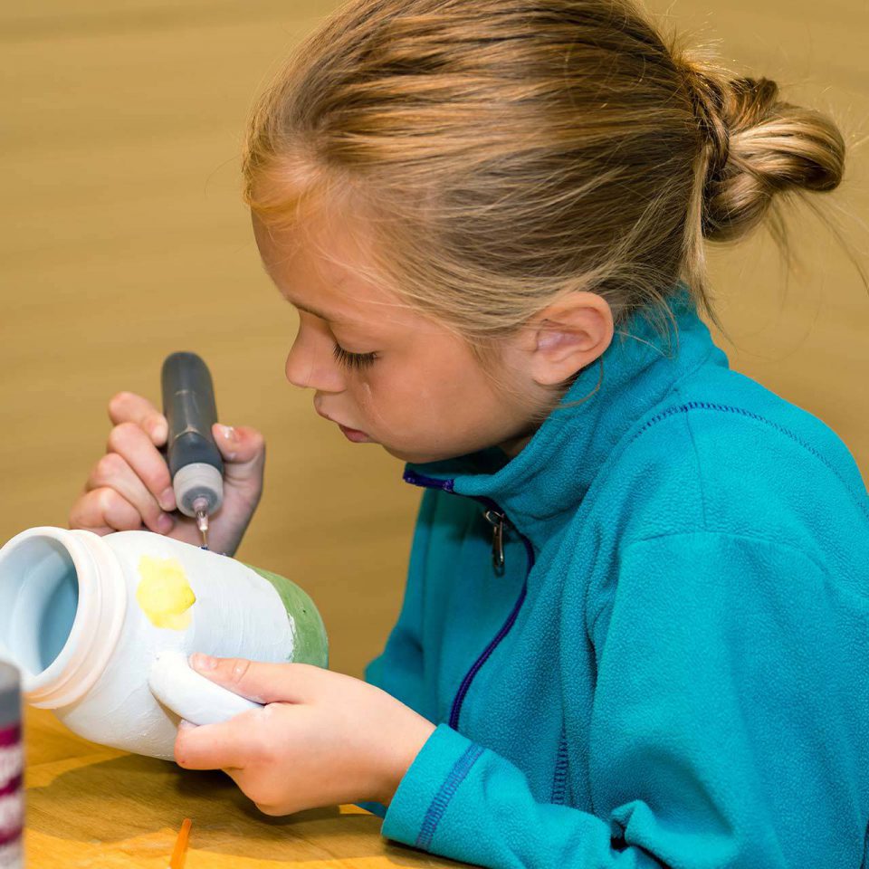 Child using a black paint pen to decorate a pottery mug at Pottery Bayou in Winona Lake, IN